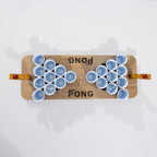 Overhead view of the Play the Field Mini Pong wooden game board with blue cups and ball launchers at each end.