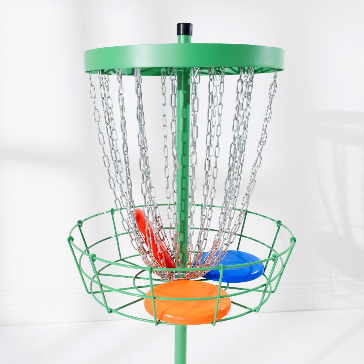 Close-up of the green disc golf target basket with silver hanging chains and colourful discs.