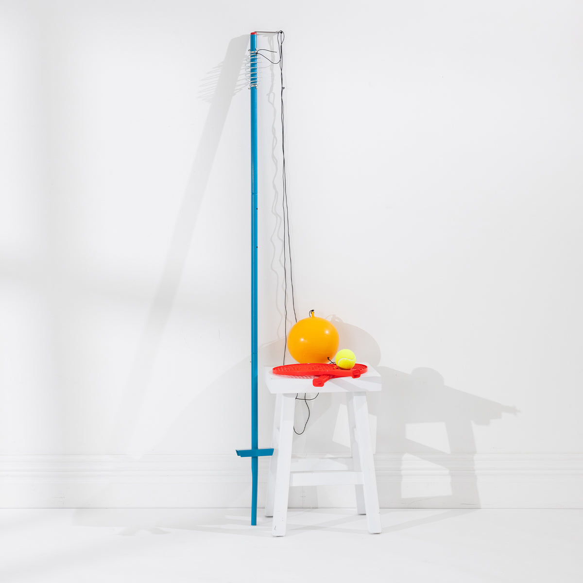Play The Field Backyard Tetherball Game with a tall blue pole, orange tetherball, yellow tennis ball and two red racquets.