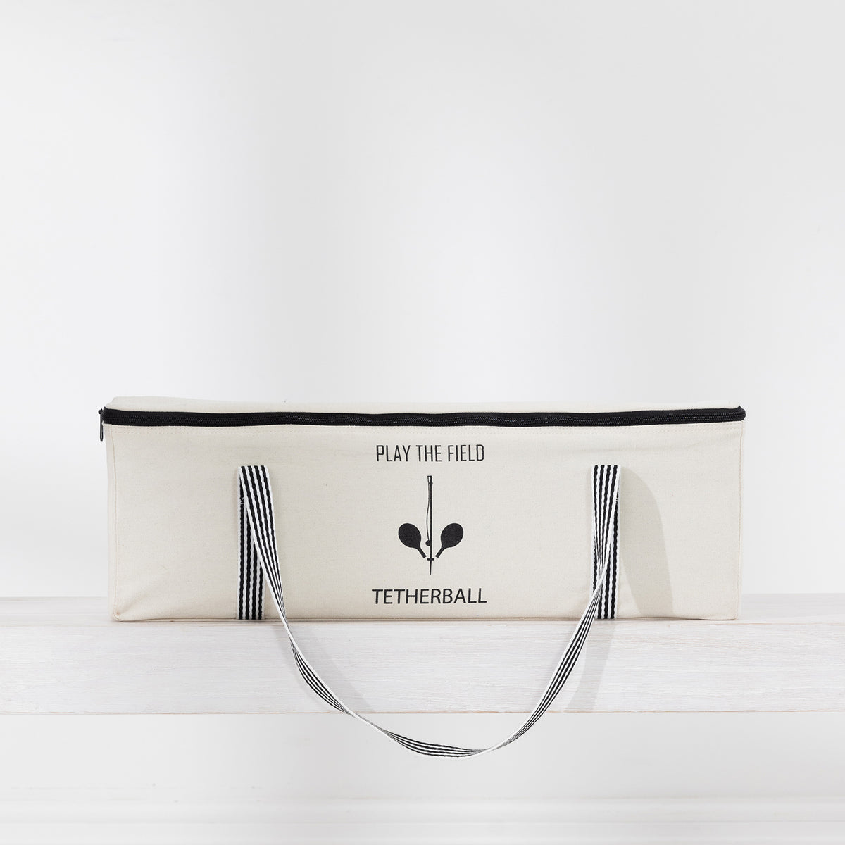 Play The Field Tetherball Game packed inside a cream canvas zip bag with black striped handles.