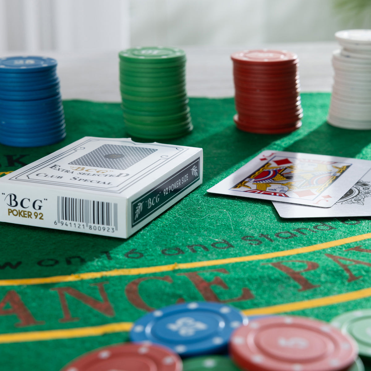 Close-up of the Play the Field Texas Card Set with poker cards and stacks of blue, green, red and white chips on the green gaming mat.