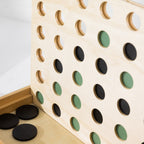 Close-up of the wooden 4-In-A-Row game board with green and black wooden coins in play.