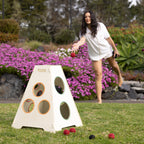 Woman playing the Play the Field Tower Ball game outdoors, throwing a red ball towards the wooden target tower.