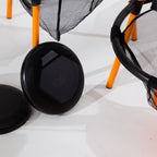 Close-up of the black flying discs beside the orange frame and mesh target.