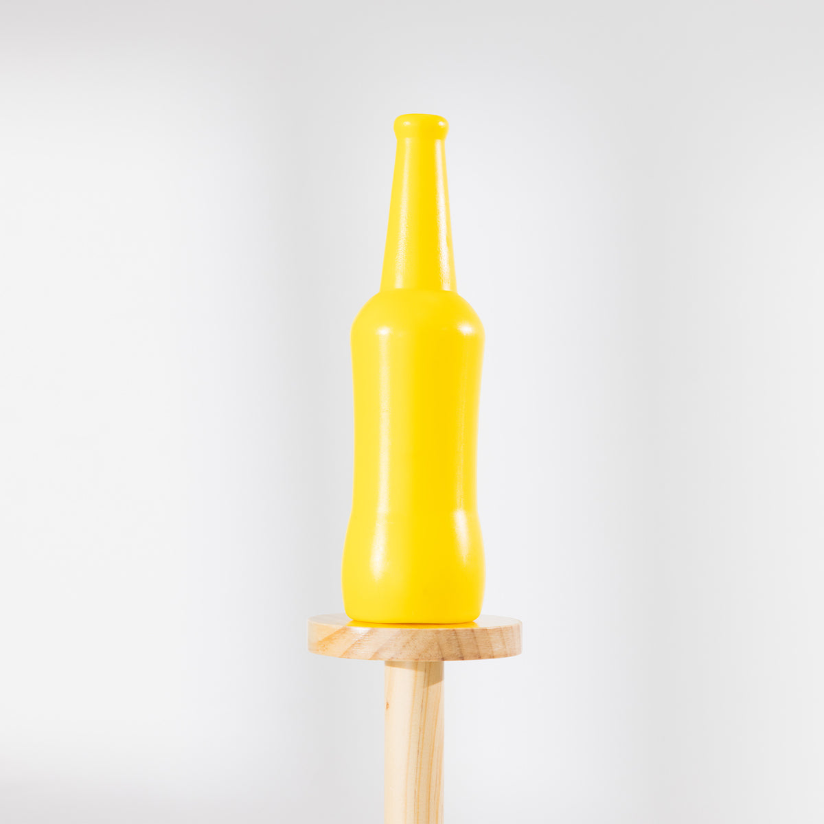 Close-up of a yellow bottle balanced on top of the wooden Disc Bottle Drop game stand.
