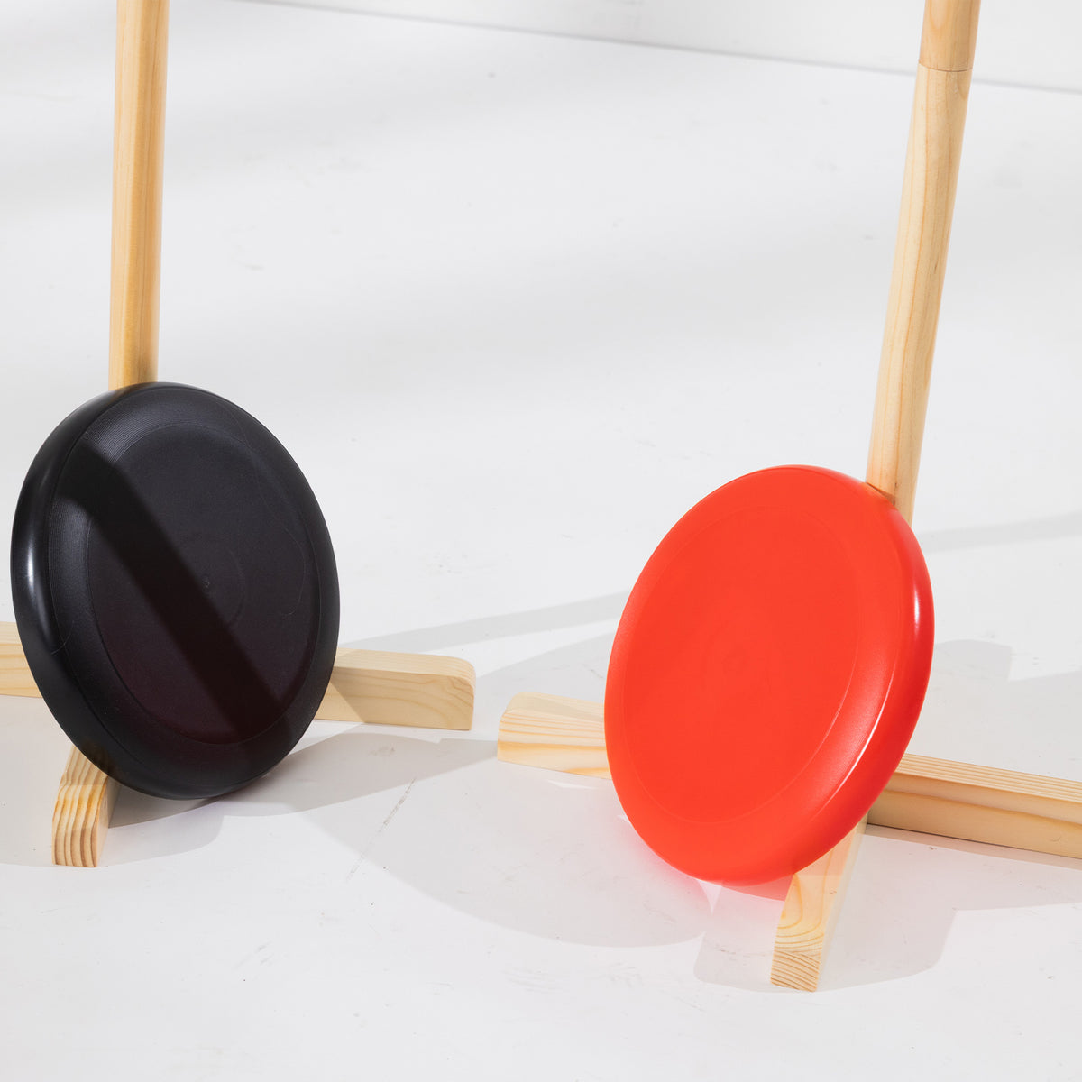 Close-up of the red and black throwing discs positioned against the wooden game stands.