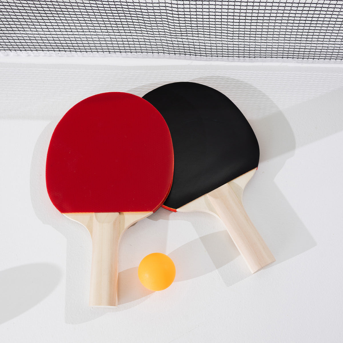 Play the Field Table Tennis Set with one red paddle, one black paddle and an orange table tennis ball displayed beneath the net.