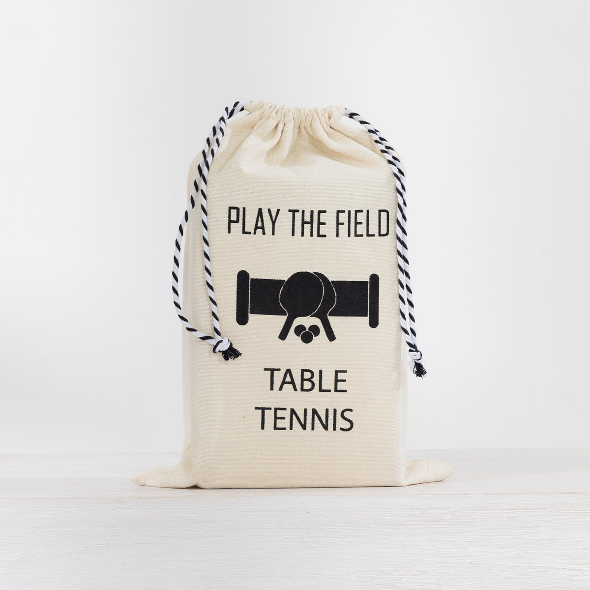 Play the Field Table Tennis Set stored in a cream drawstring carry bag with black printed detailing.