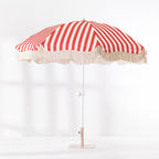 Red and white striped patio umbrella with cream tassel edging shown open from the front.