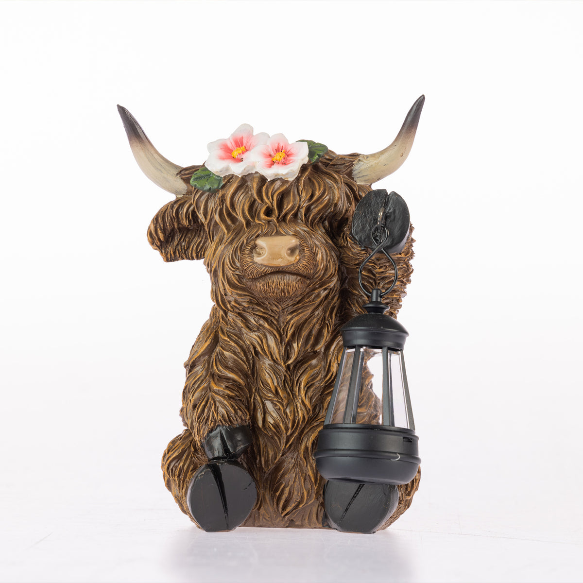 A Highland cow figurine with long brown hair, holding a black lantern and wearing a flower crown, photographed on a white background.