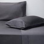 Gray pillowcases on a bed with a plain background