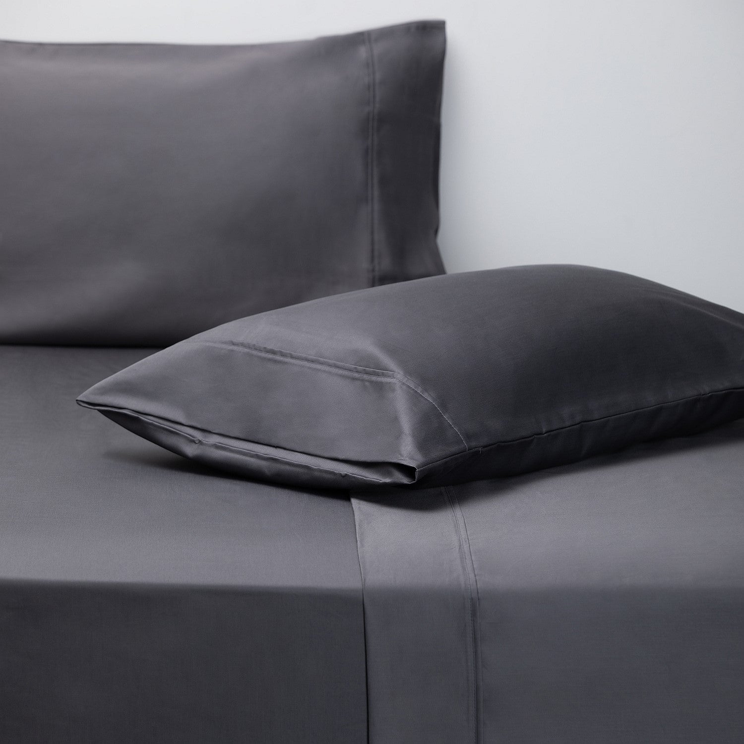 Gray pillowcases on a bed with a plain background