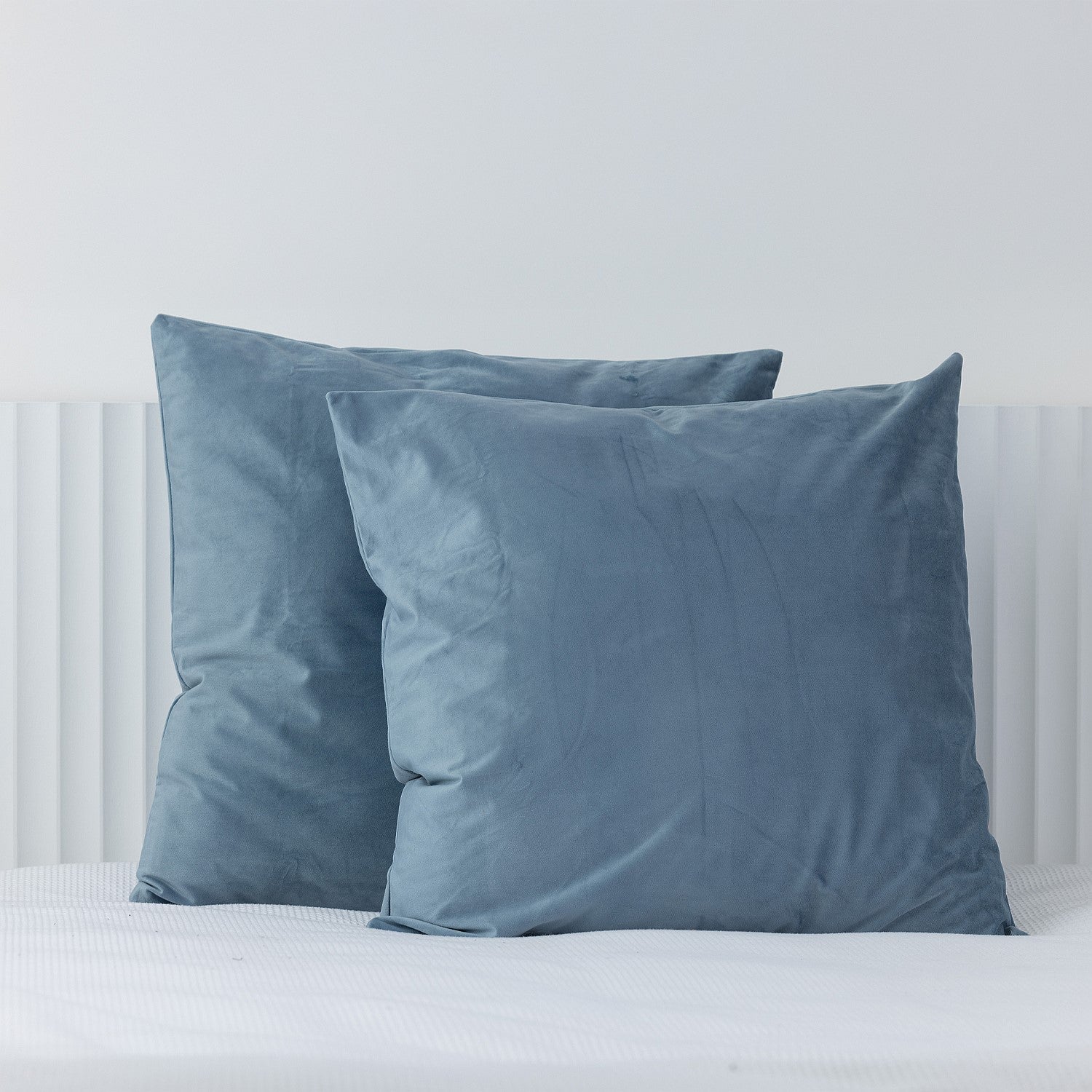 Blue European velvet pillowcases styled on a white bed.