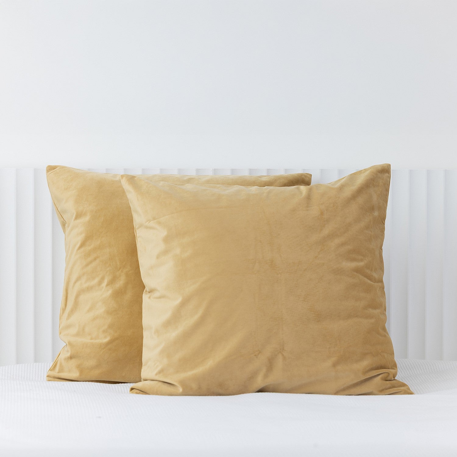 Mustard European velvet pillowcases styled on a white bed.