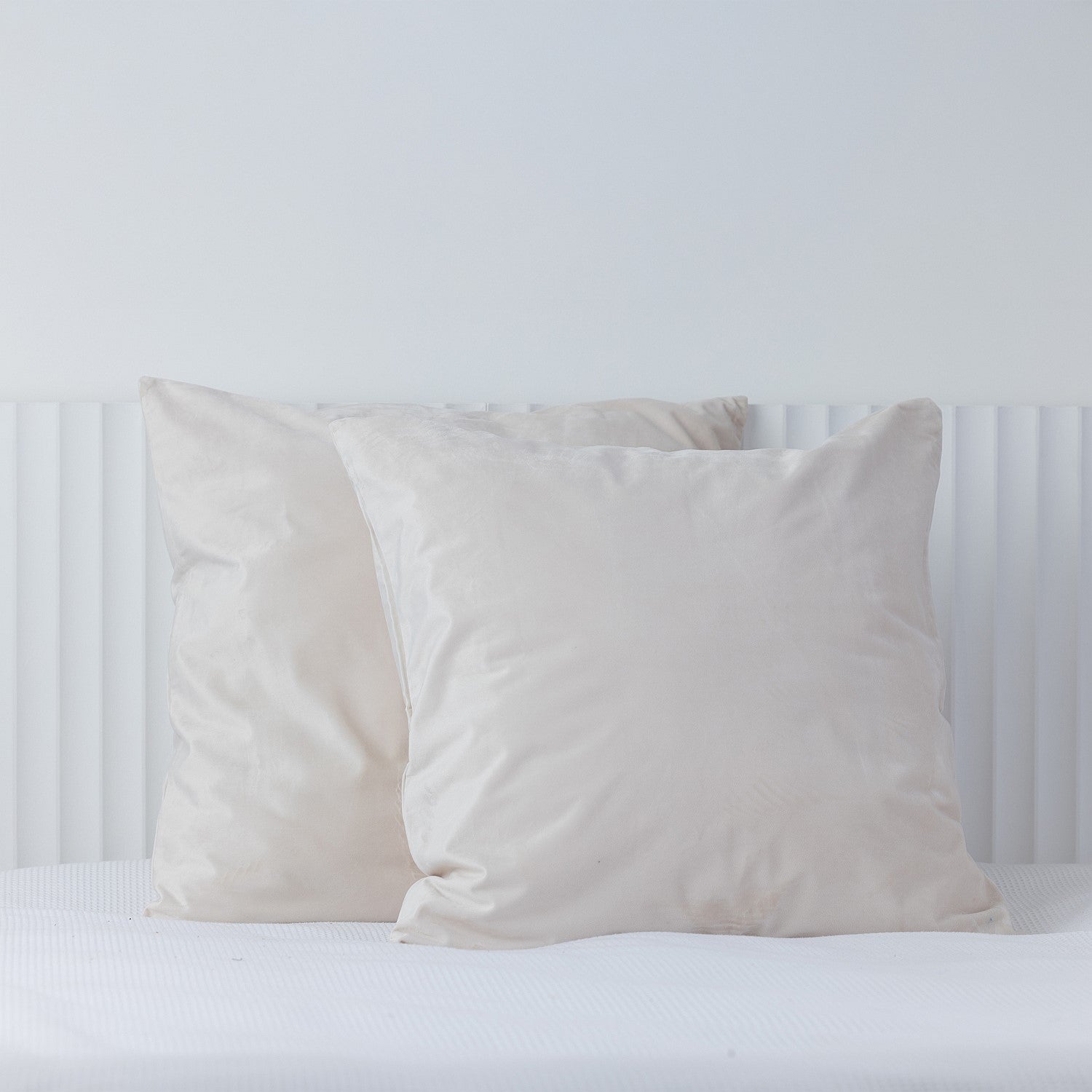 Off white European velvet pillowcases styled on a white bed.