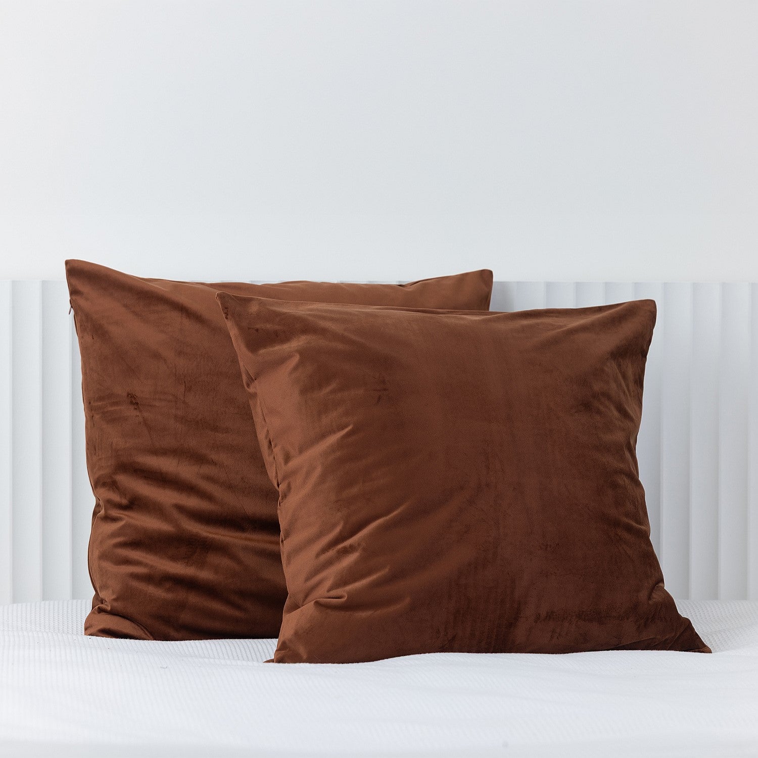 Rust brown European velvet pillowcases styled on a white bed.