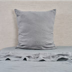 Gray pillow and bedding on a bed with a neutral background