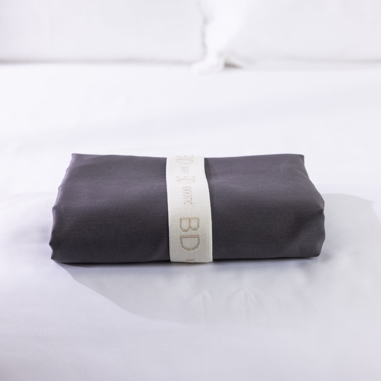 A neatly folded body pillowcase is secured with a reusable branded storage band, showcasing premium presentation and effortless linen organisation.