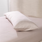 A linen body pillow is dressed in a smooth cotton pillowcase and styled on a neatly made bed, showcasing its clean, luxurious finish and full-length comfort.