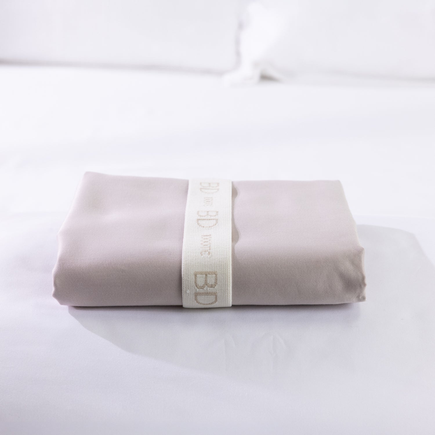 A neatly folded body pillowcase is secured with a reusable branded storage band, showcasing premium presentation and effortless linen organization.