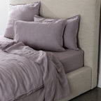 Gray bedding set on a bed with a neutral headboard.