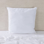 White pillow on a bed with a beige headboard