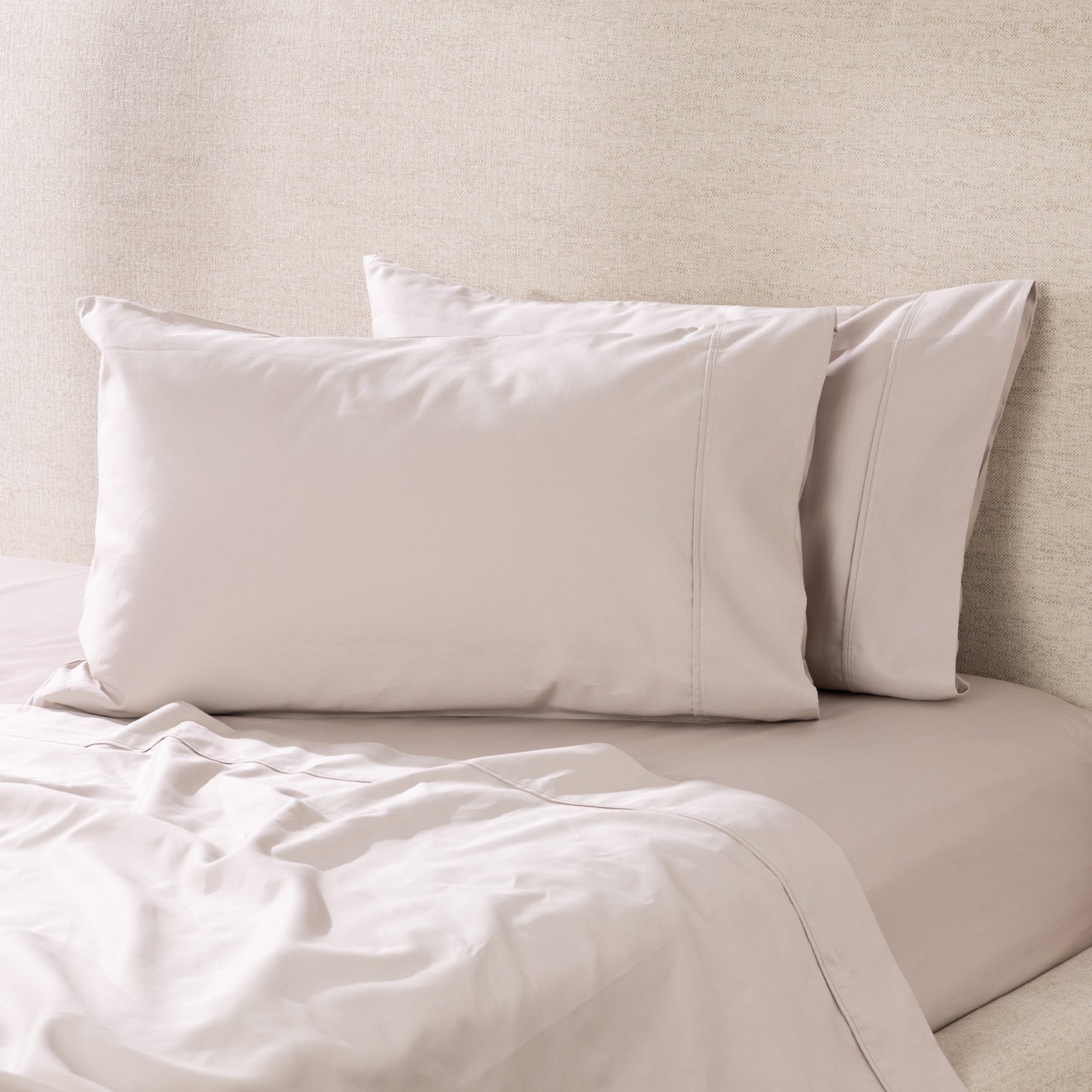 A pair of linen pillowcases is beautifully styled on a freshly made bed, showcasing their smooth, luxurious finish and timeless elegance.