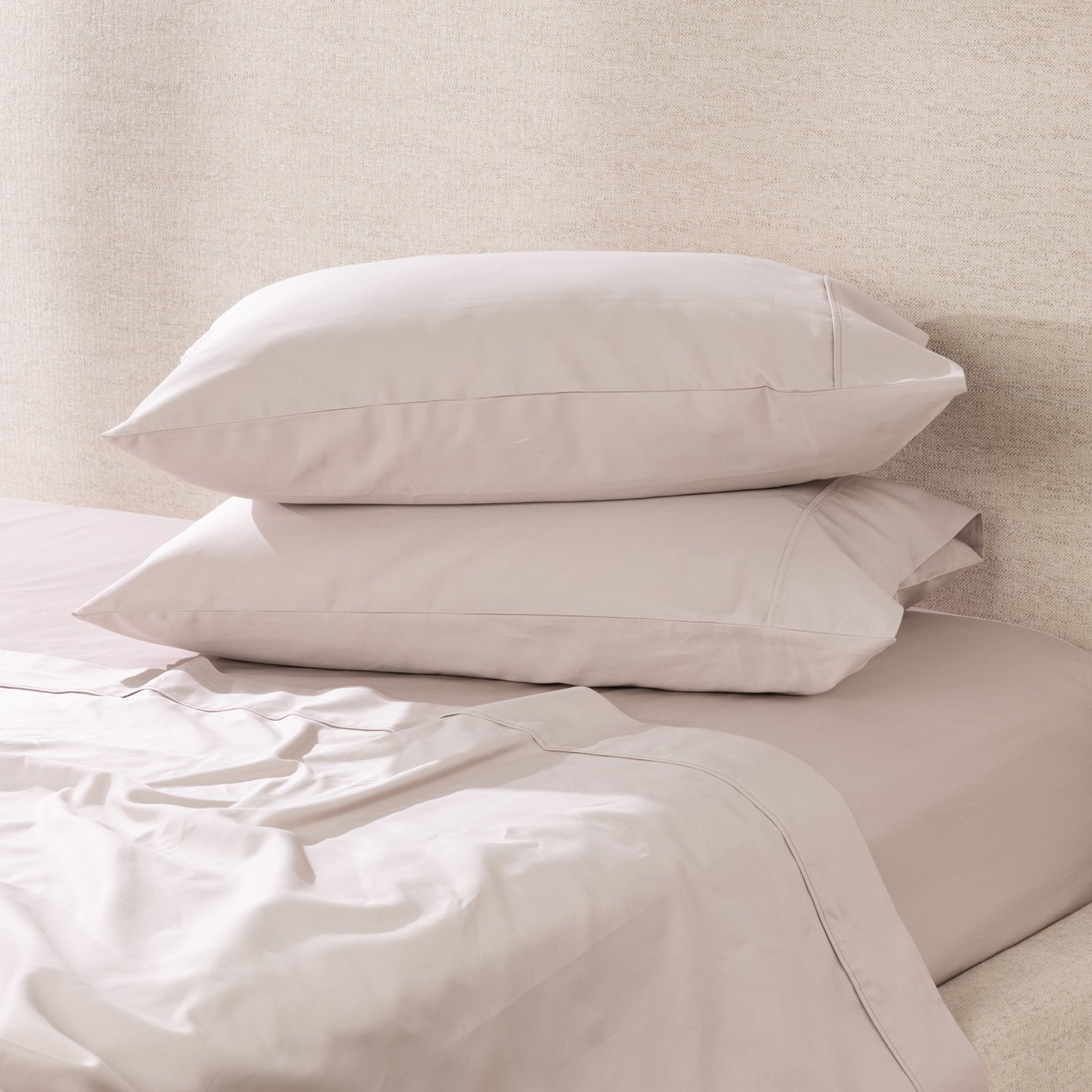 A pair of linen pillowcases is beautifully styled on a freshly made bed, showcasing their smooth, luxurious finish and timeless elegance.
