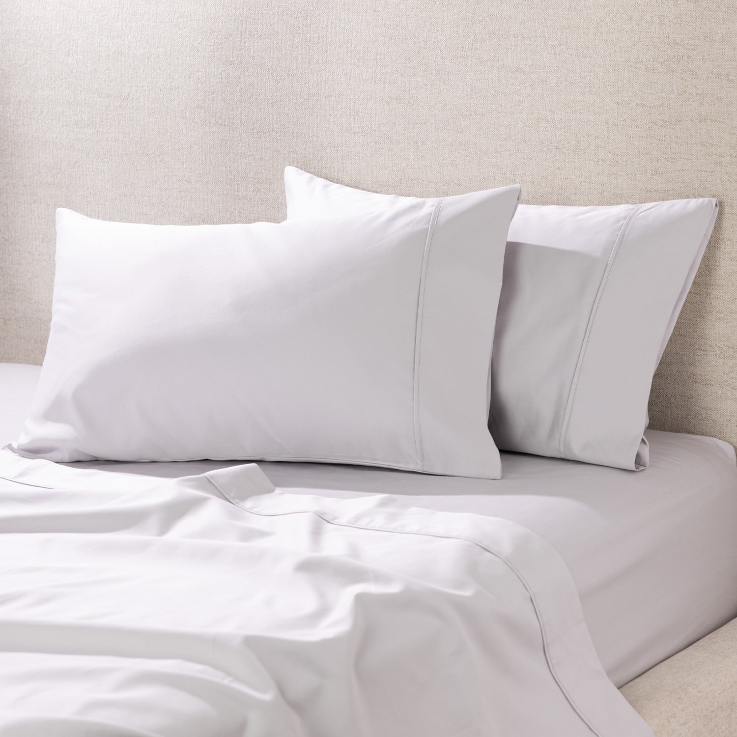 A pair of silver pillowcases is beautifully styled on a freshly made bed, showcasing their smooth, luxurious finish and timeless elegance.