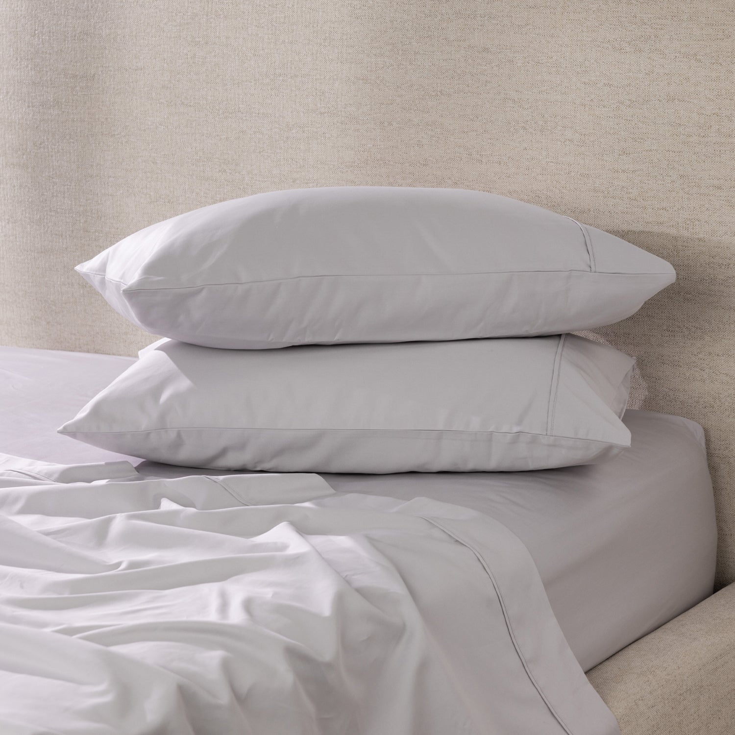 A pair of silver pillowcases is beautifully styled on a freshly made bed, showcasing their smooth, luxurious finish and timeless elegance.