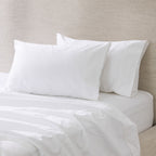 A pair of crisp white pillowcases is beautifully styled on a freshly made bed, showcasing their smooth, luxurious finish and timeless elegance.