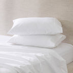 A pair of crisp white pillowcases is beautifully styled on a freshly made bed, showcasing their smooth, luxurious finish and timeless elegance.