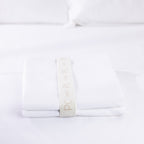 A neatly folded white pillowcase pair is secured with a reusable branded storage band, showcasing premium presentation and effortless linen organisation.