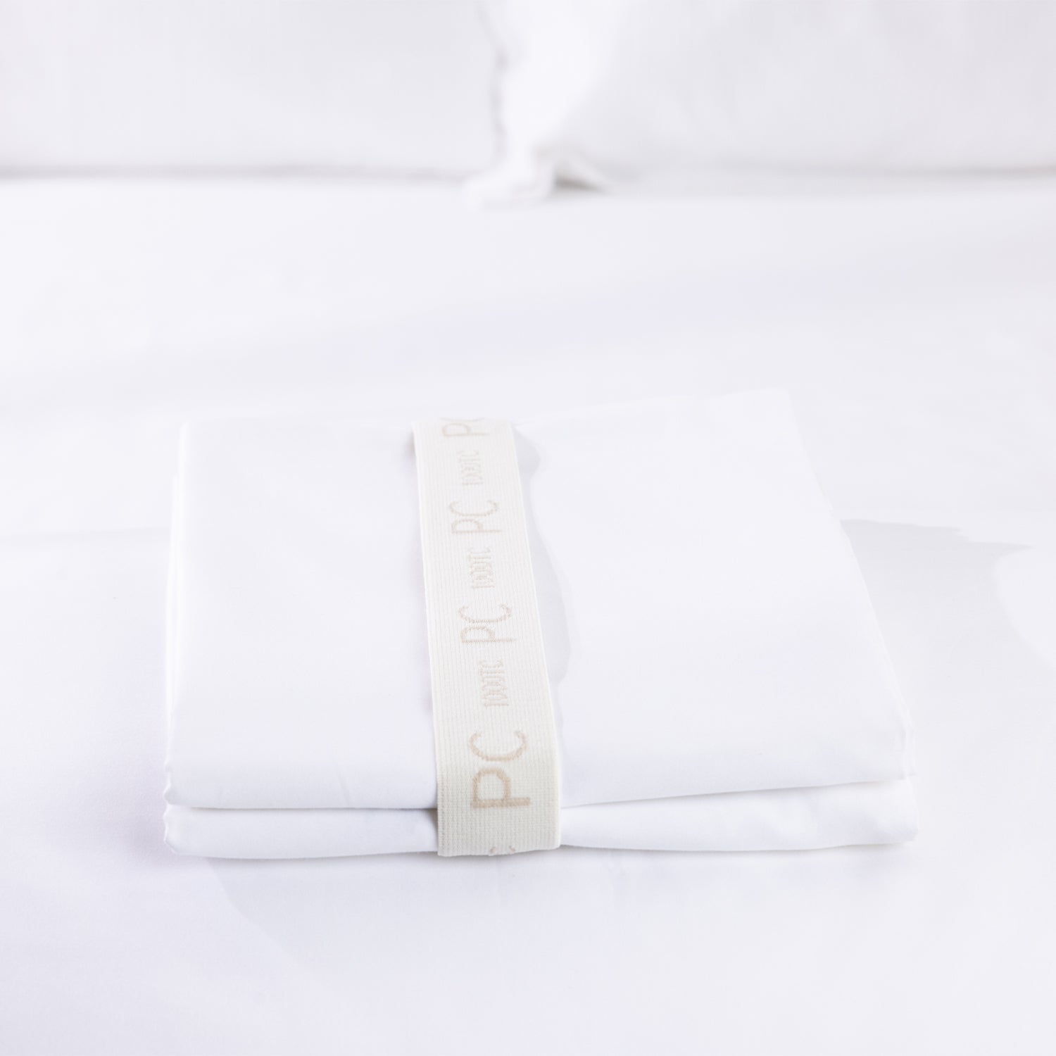 A neatly folded white pillowcase pair is secured with a reusable branded storage band, showcasing premium presentation and effortless linen organisation.