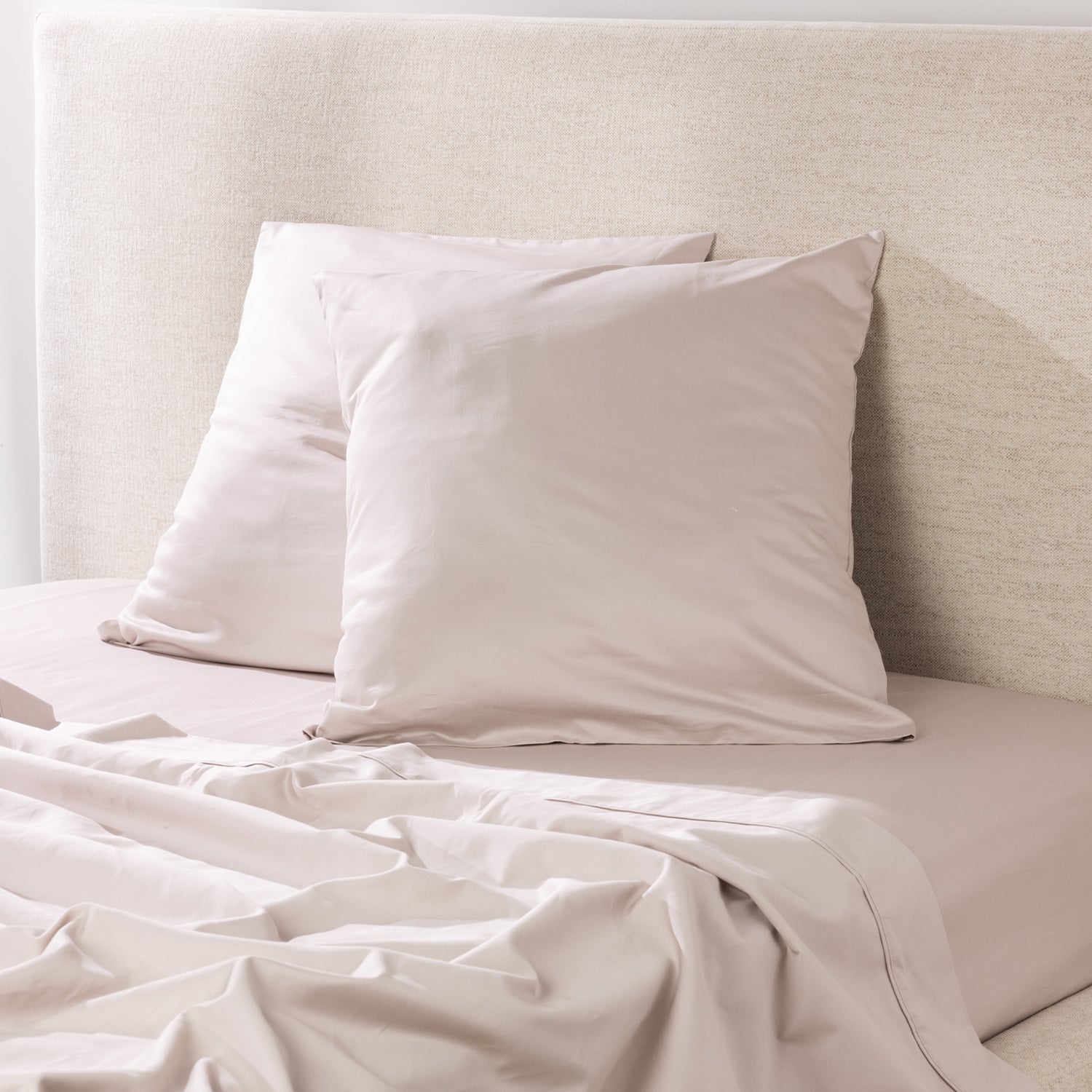 A pair of linen European pillowcases is styled on coordinating bedding, creating a sophisticated, contemporary bedroom look with a smooth, luxurious finish.