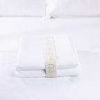 A neatly folded white European pillowcase set is secured with a reusable branded storage band, showcasing premium presentation and elegant linen organisation.