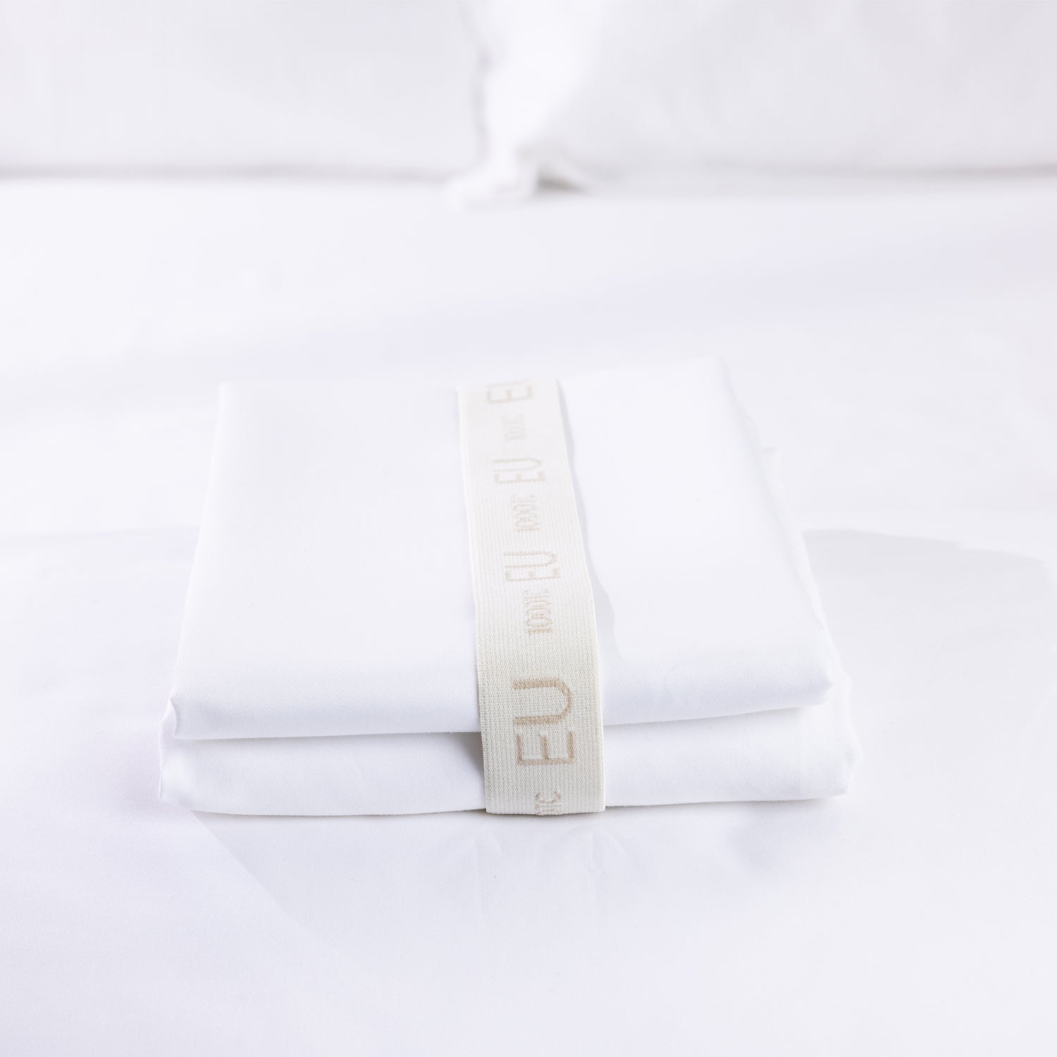 A neatly folded white European pillowcase set is secured with a reusable branded storage band, showcasing premium presentation and elegant linen organisation.
