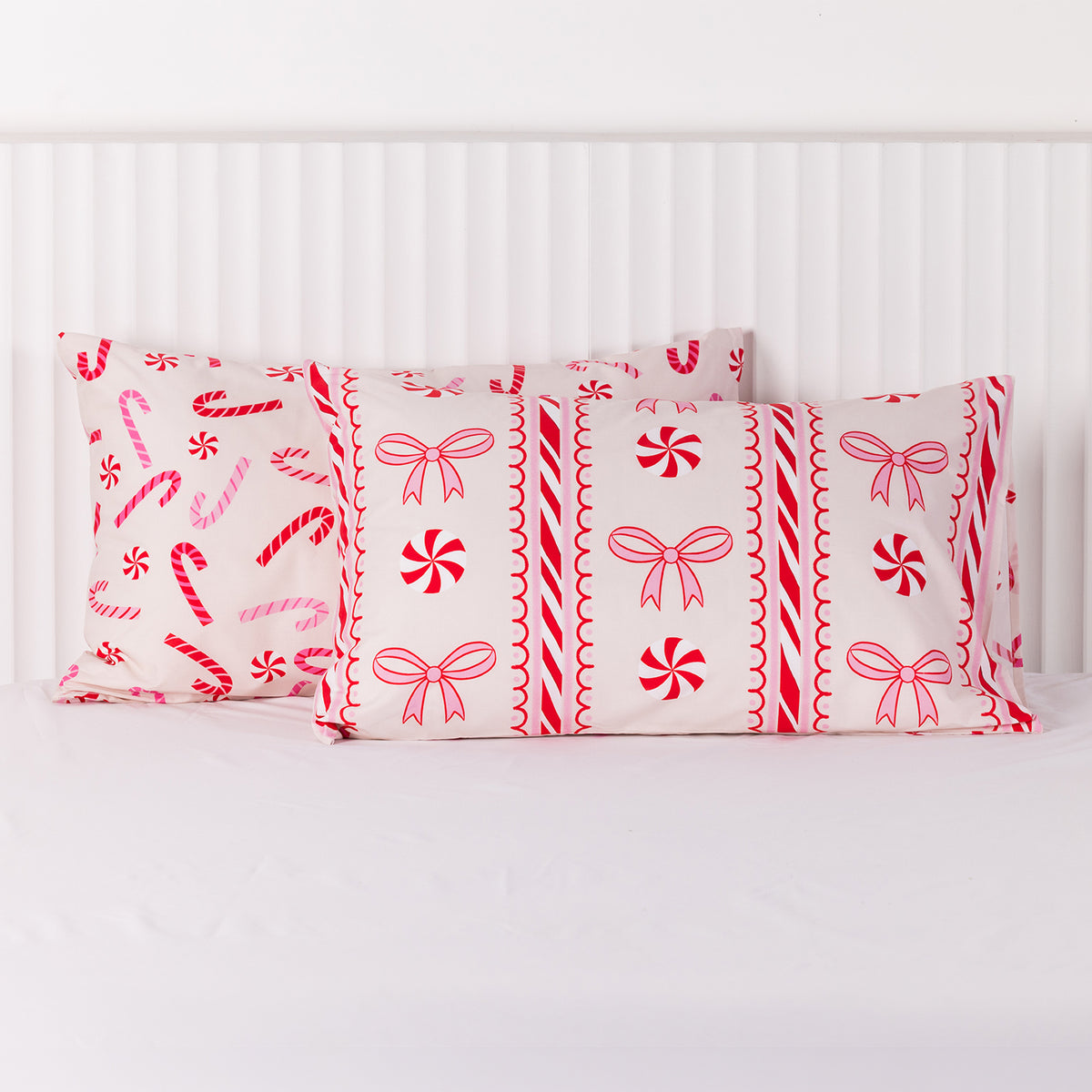 Christmas Wishes Candy Cane Christmas Pillowcase Pair featuring festive red and pink candy canes, peppermint swirls, bows and decorative stripes on a soft pink background.