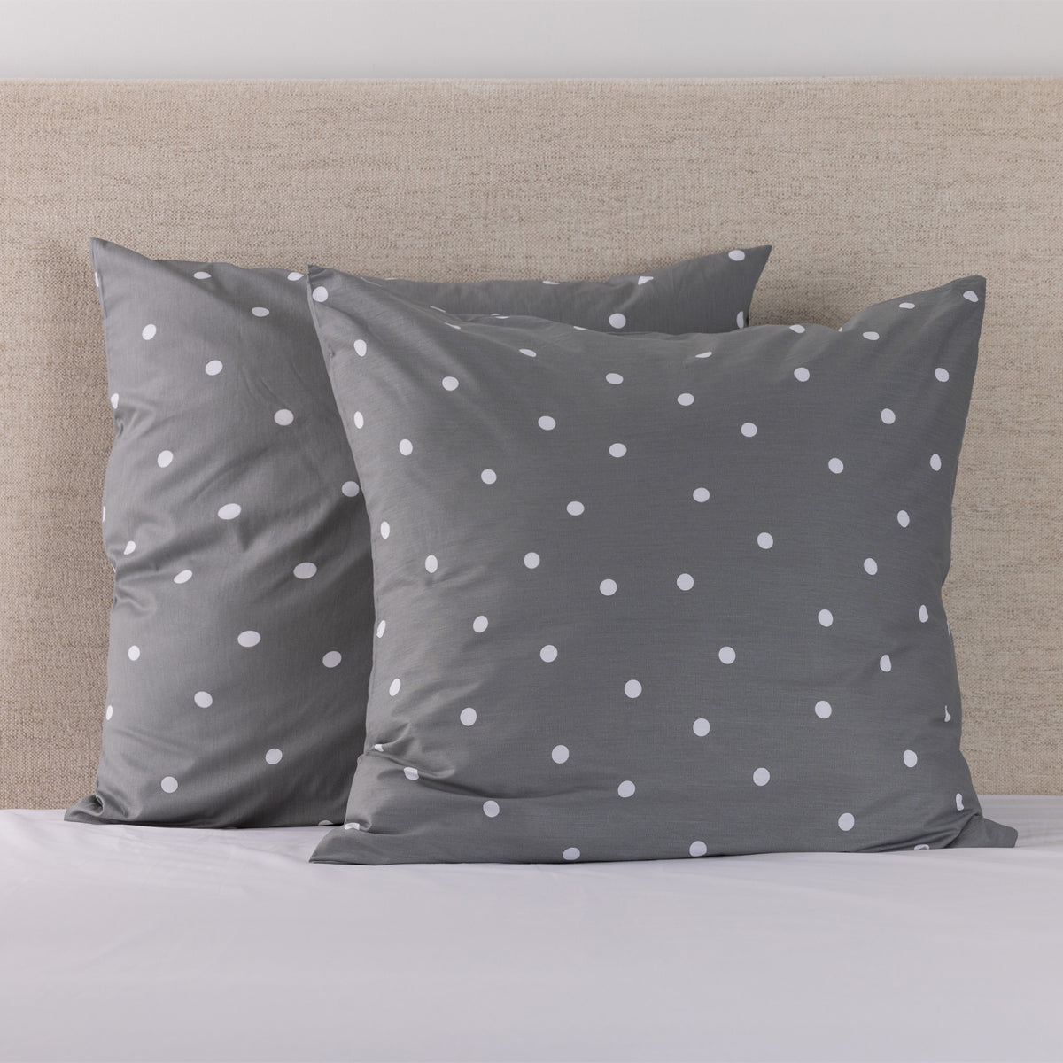 Pure & Simple Monroe European Pillowcase Pair in navy with white polka dots, styled on a bed against a neutral upholstered headboard.
