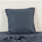 A midnight linen Euro pillowcase is elegantly styled against a neutral textured backdrop, highlighting its generous square shape, natural linen texture and relaxed, timeless appeal.