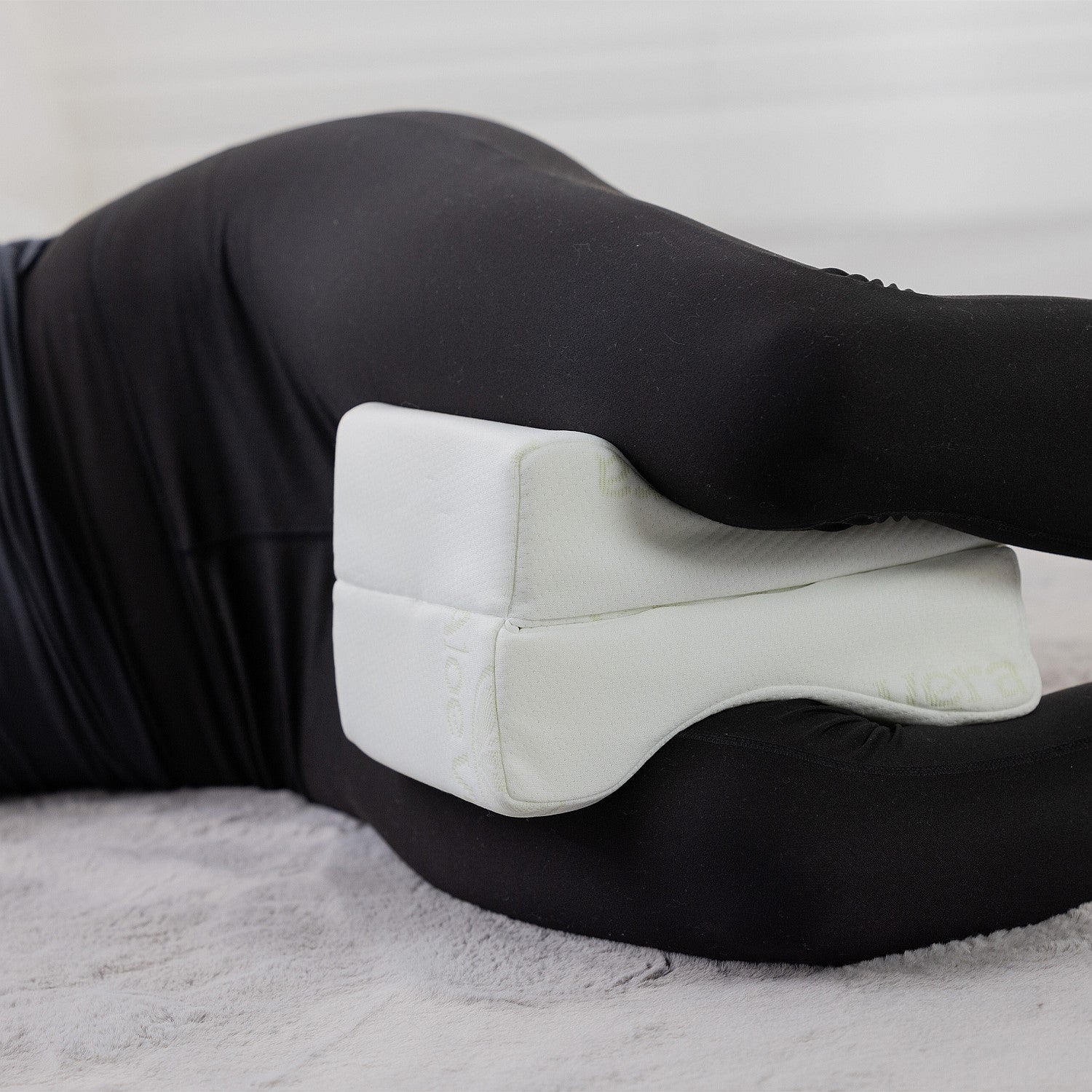 Aloe Vera memory foam leg pillow positioned between the knees to support side sleeping alignment.