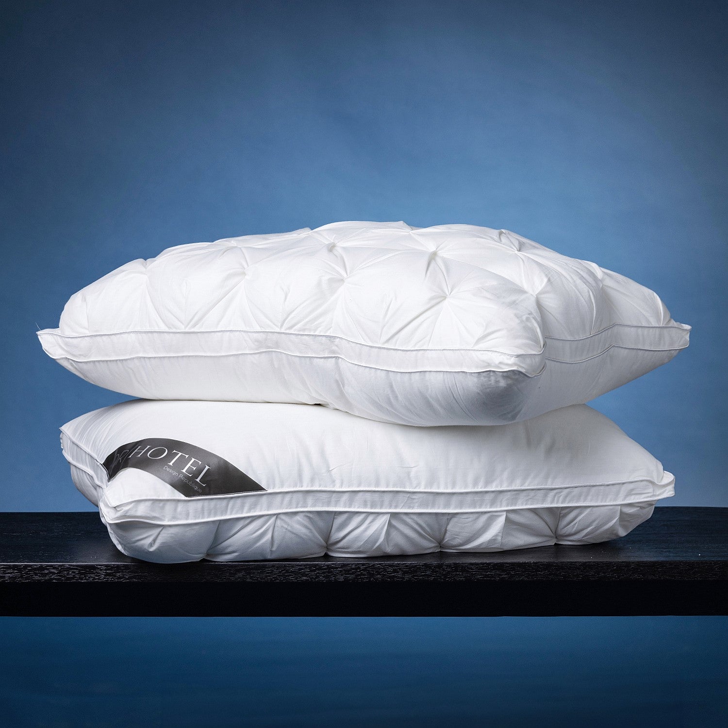 Two white pinch-pleat pillows stacked together, showcasing the plush loft, decorative texture, and piped edge finish of the Dr Hotel  Pillow.

