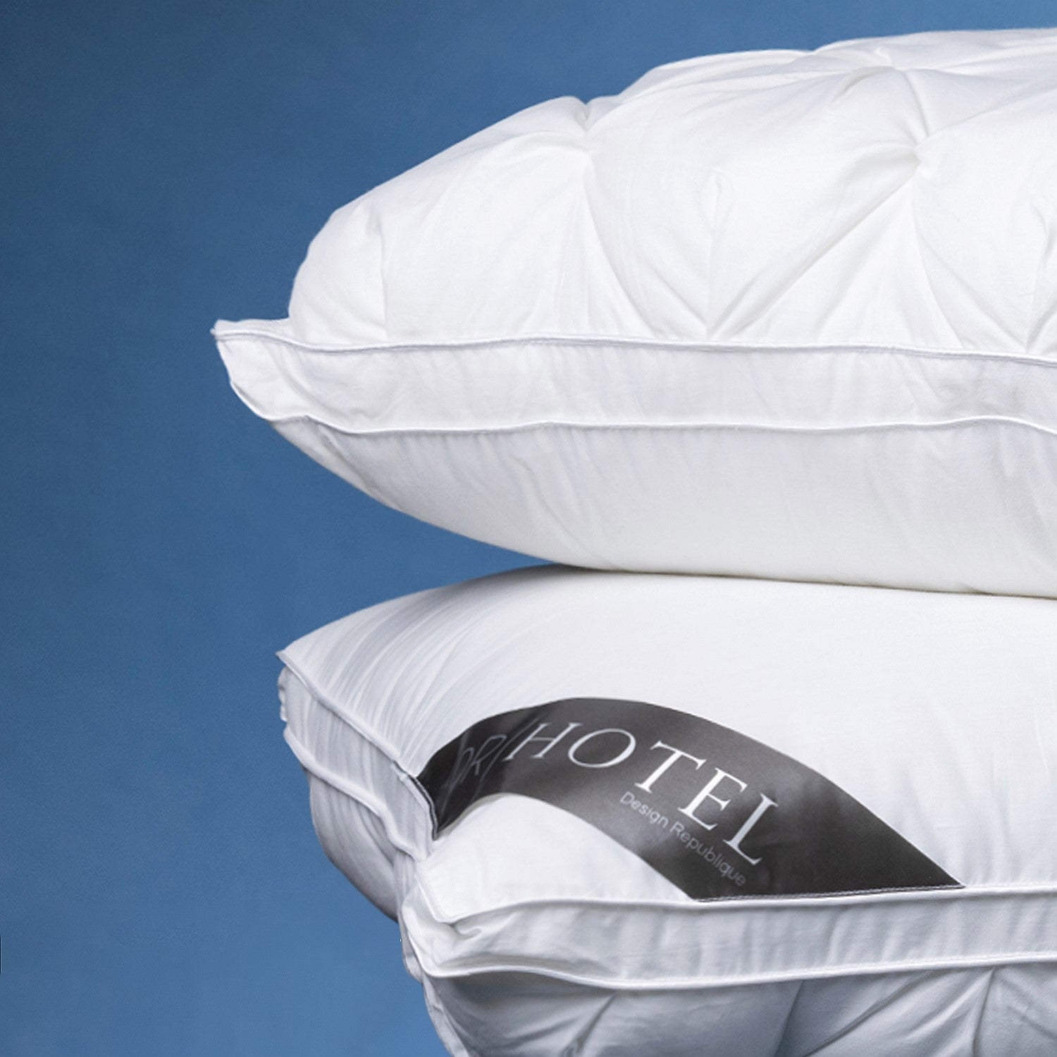 Close-up of stacked white pinch-pleat pillows, highlighting the decorative texture, piped edges, and luxurious loft.