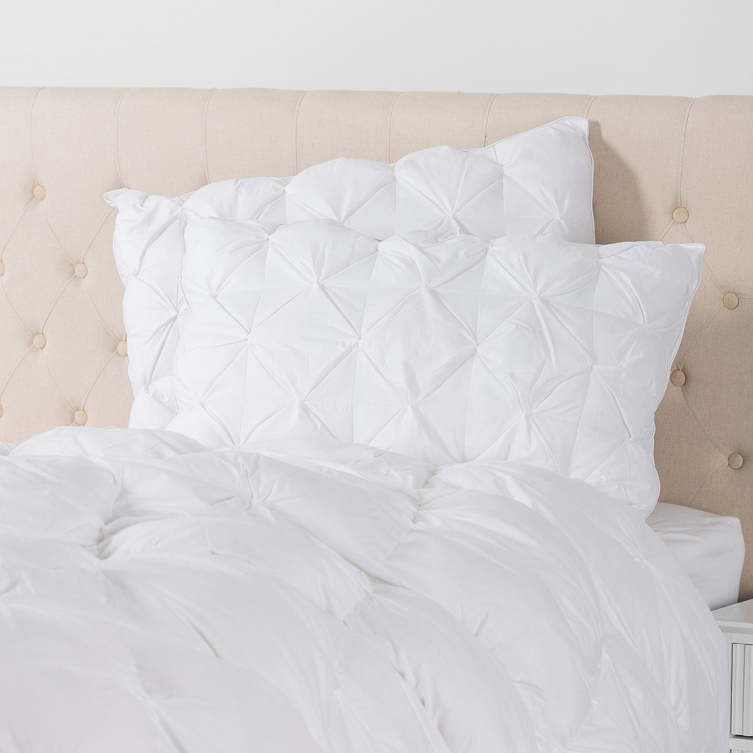 White pinch-pleat pillows styled on a bed, adding texture, comfort, and hotel-inspired elegance to the bedroom.