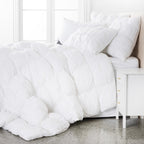 Complete bedding ensemble featuring pinch-pleat pillows and matching duvet, creating a plush and sophisticated hotel-style bedroom setting.