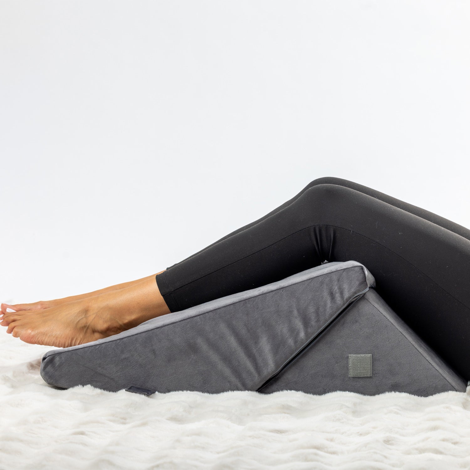 Solace Multi-Purpose Wedge Support Pillow positioned beneath the knees to provide elevated leg support.