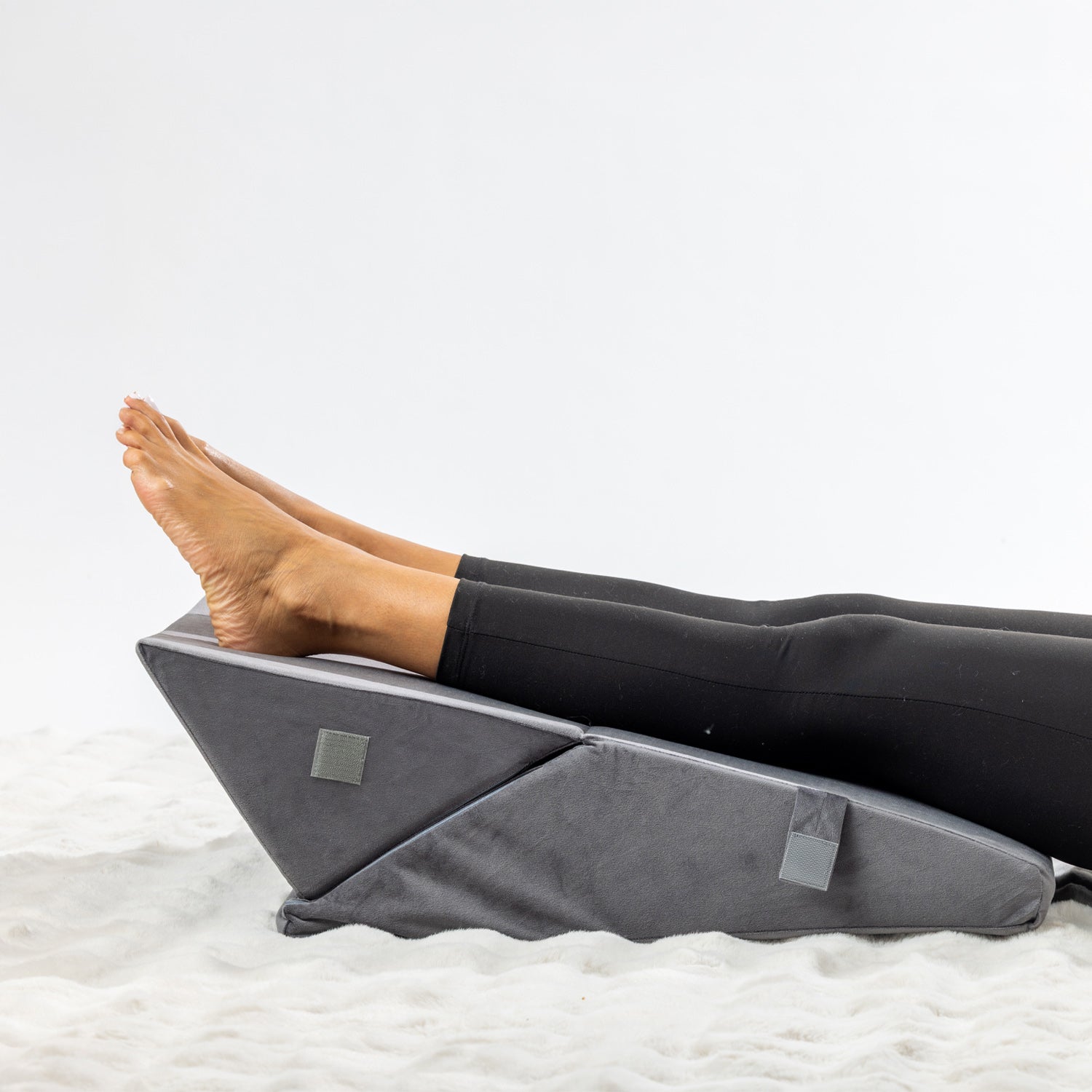 Solace Multi-Purpose Wedge Support Pillow positioned under the lower legs and feet for elevation.