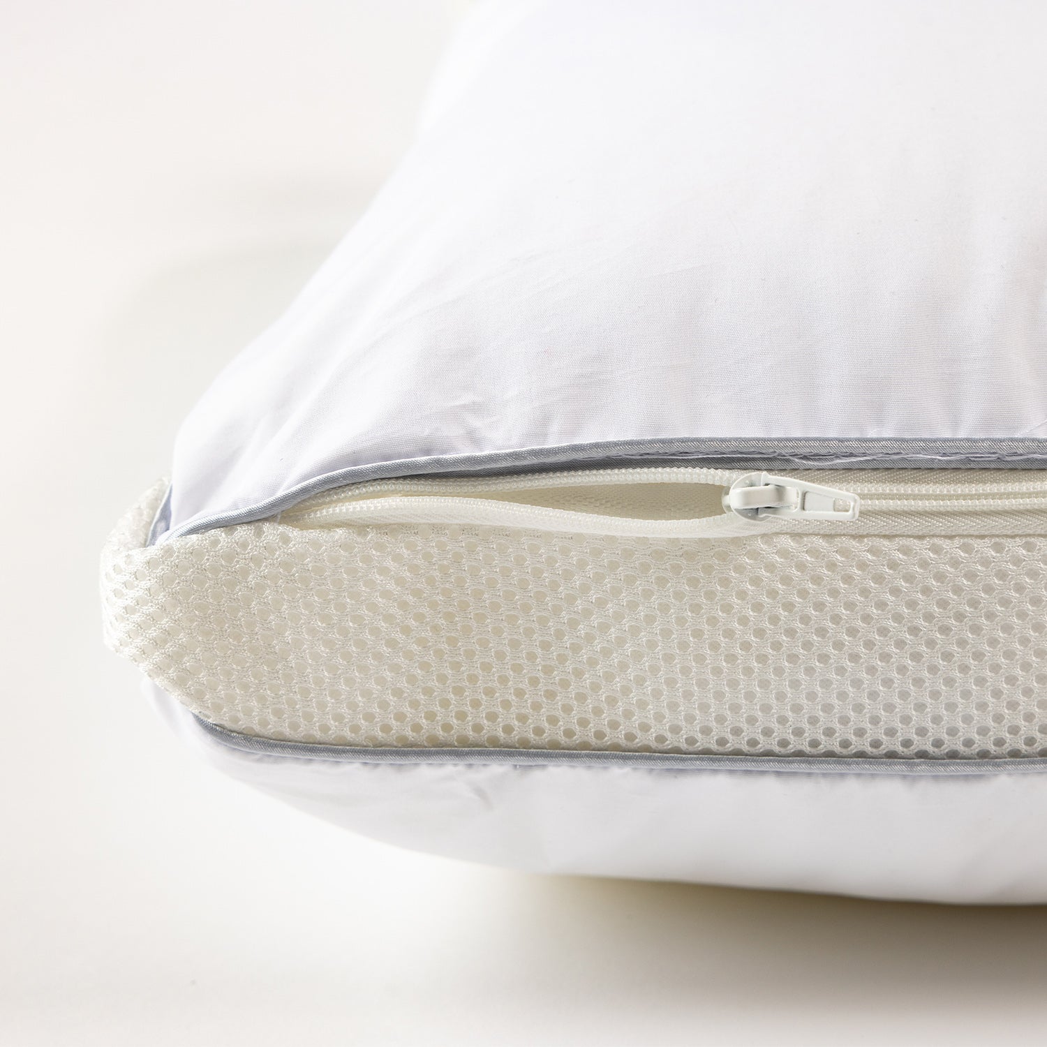 Close-up of an adjustable pillow with a zippered opening and removable foam core insert for customised height and support.
