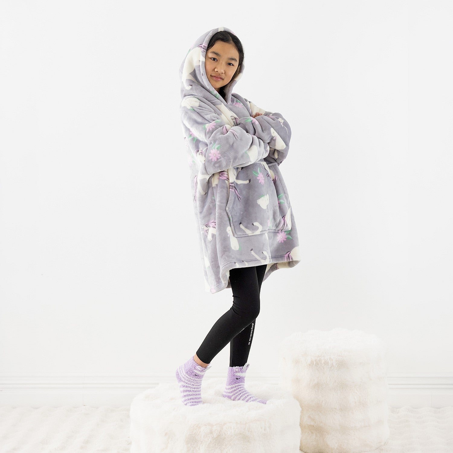 Child wearing a purple unicorn print hooded towel while standing on a white rug.