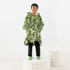 Child wearing a green dinosaur print hoodie while standing on a white stool.
